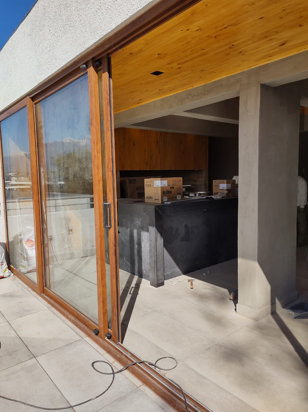 Cocina exterior de quincho con cubierta de piedra y parrilla